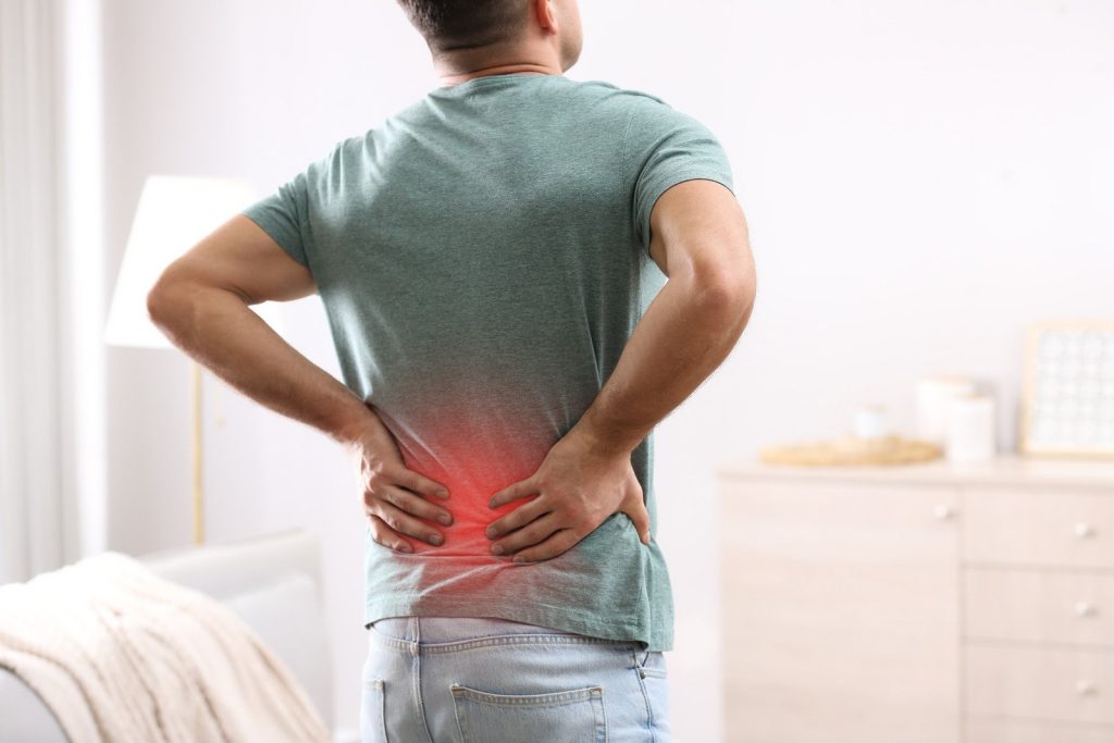 man holding his lower back in pain, with red highlight indicating back discomfort